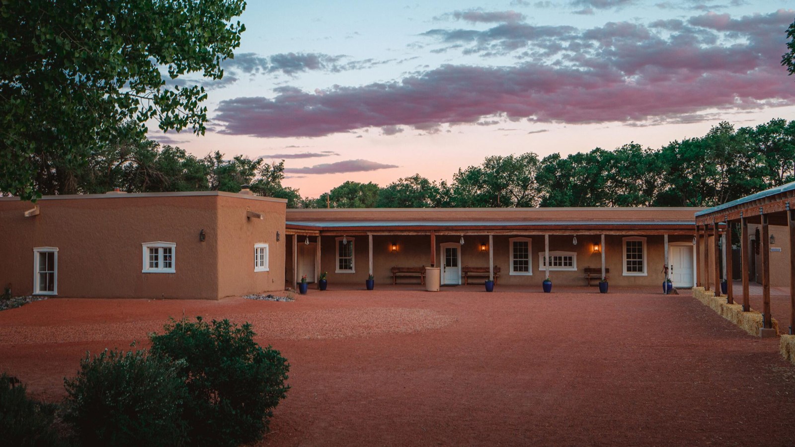 A pink-hued sunset sky, above a single story adobe building.