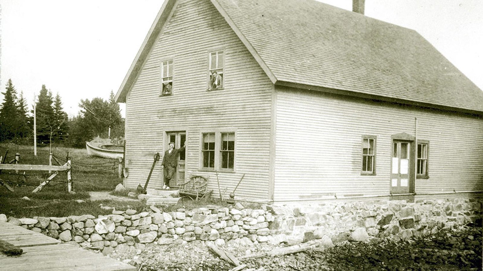 two men hang out of the windows of a building, one man in front, B&W photo