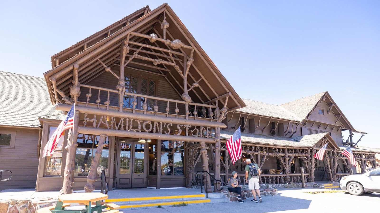 A two story wooden building with a porch and awning made of knobby wood.