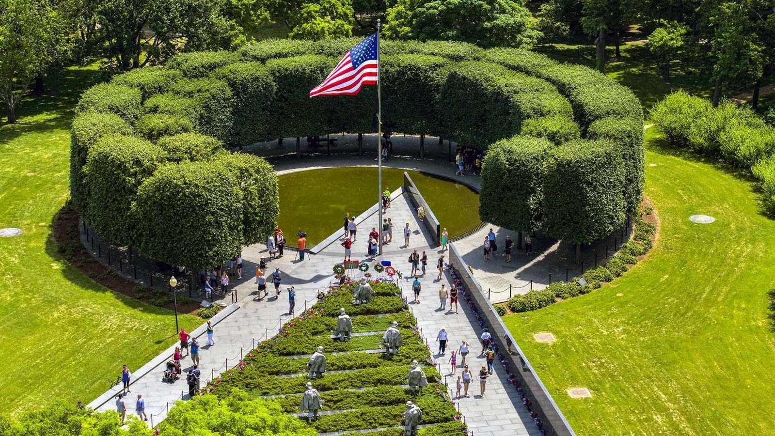 Circular area with flag, mostly surrounded by shrubbery, with two paths intersecting to form a 