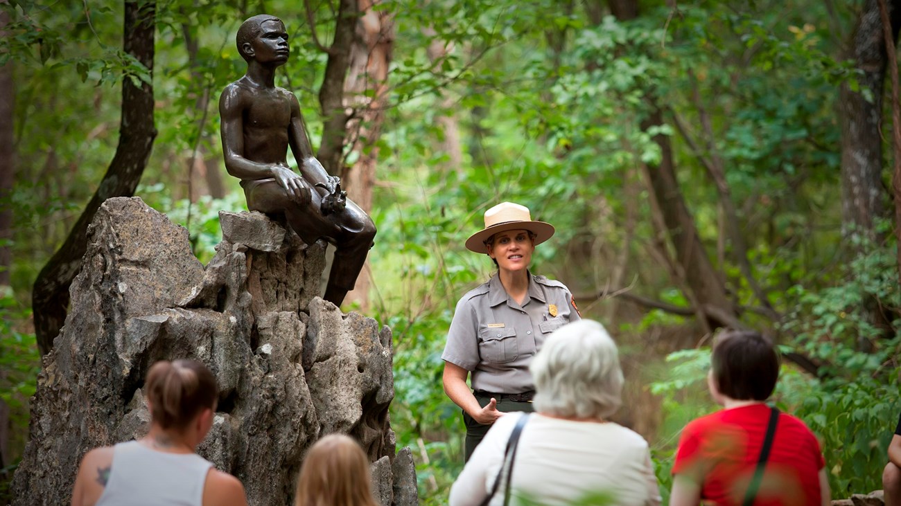 A park ranger conducting a guided tour to three adults and one child. 