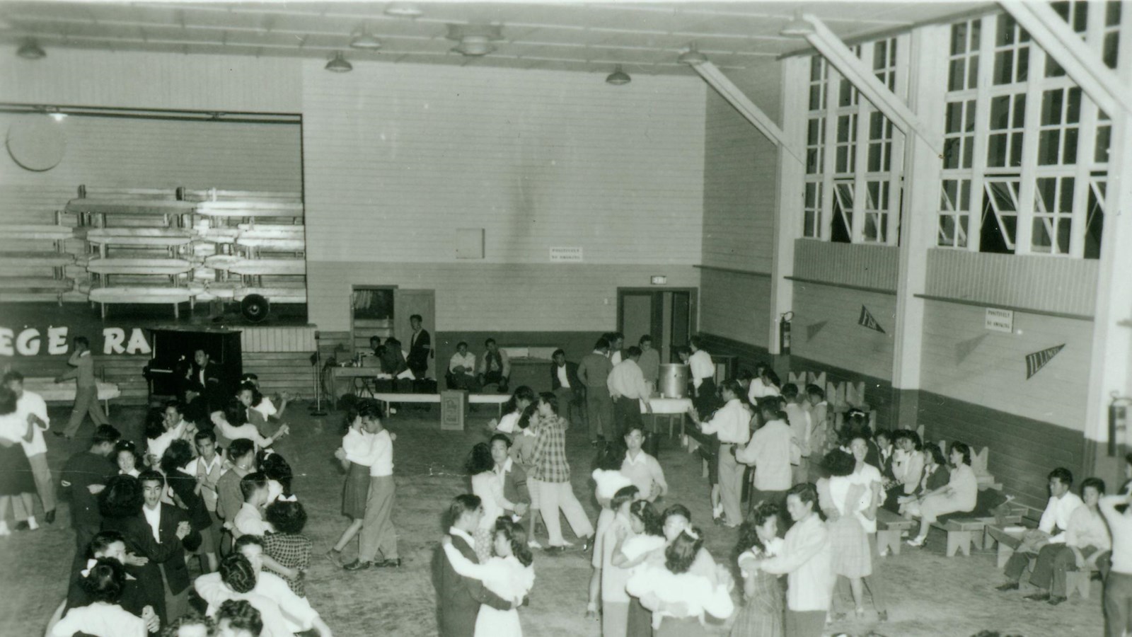 Black and white photo of young people dancing inside large building