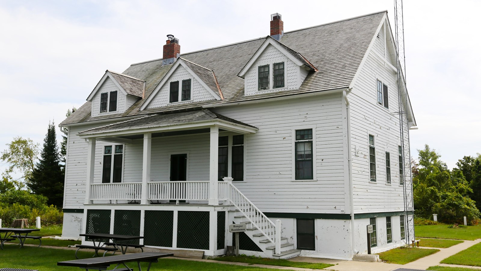 White clapboard building with three gabled dormer windows and covered front porch