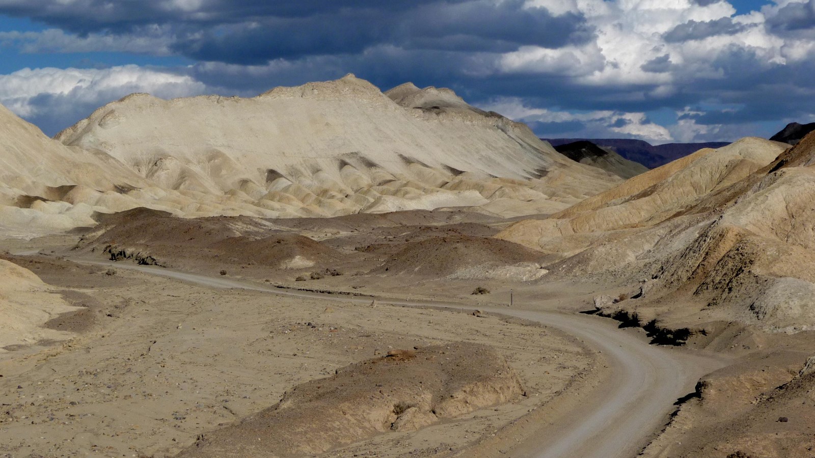 An unpaved road winds through the yellow hills of Twenty-mule Team Canyon.