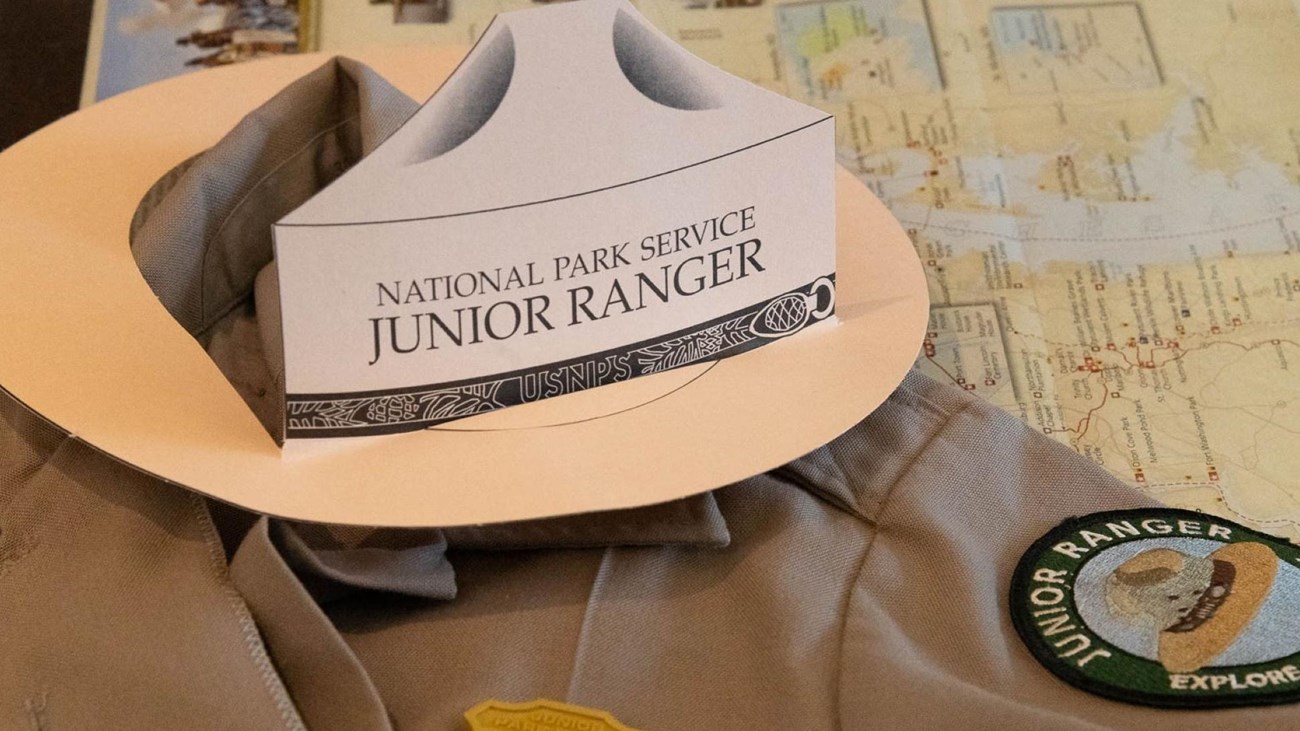 A shirt with a junior ranger badge, patch and hat on it.