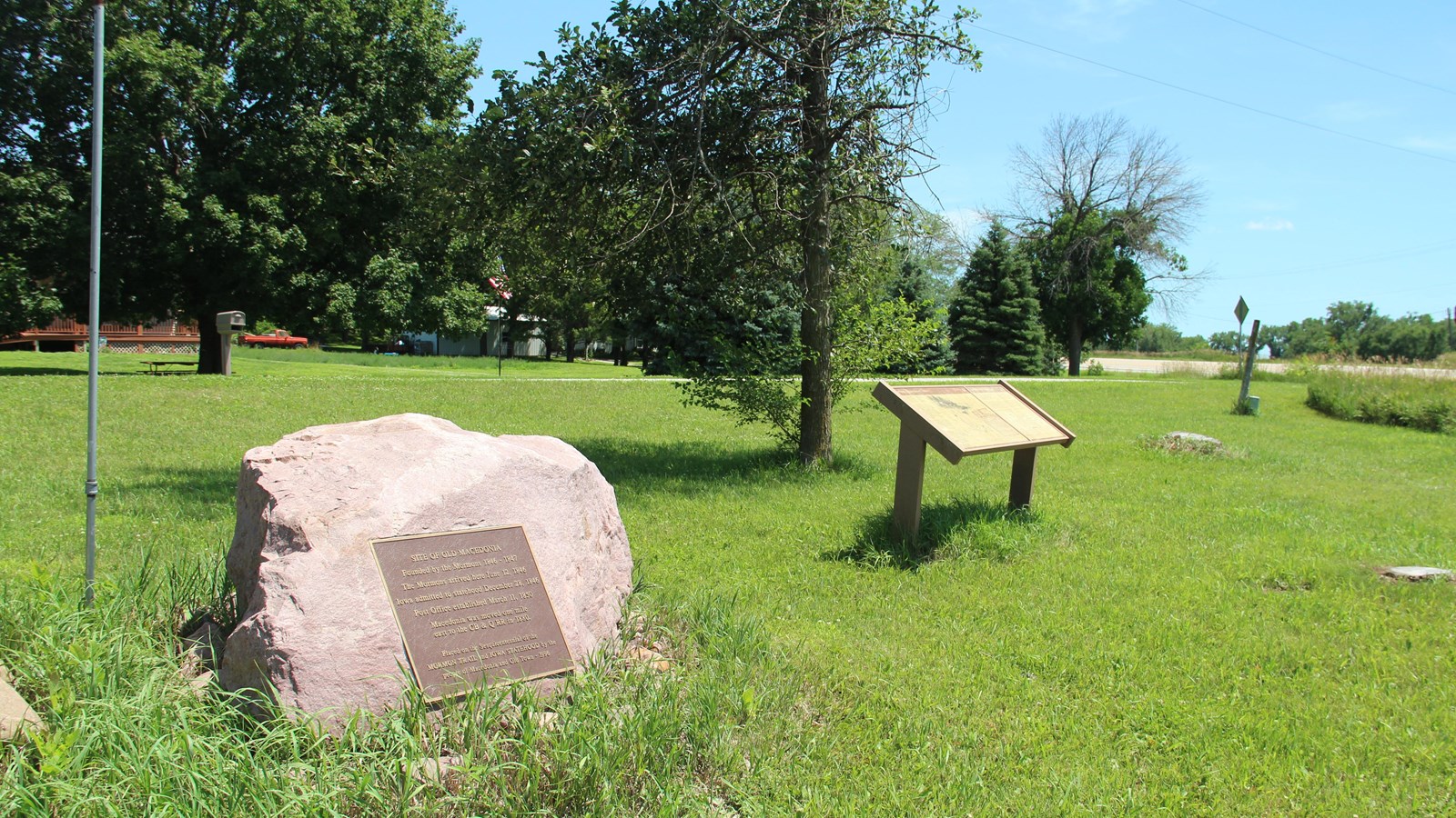 At the lower left corner of the image, a large, pink granite boulder with a brown metal plaque sits 