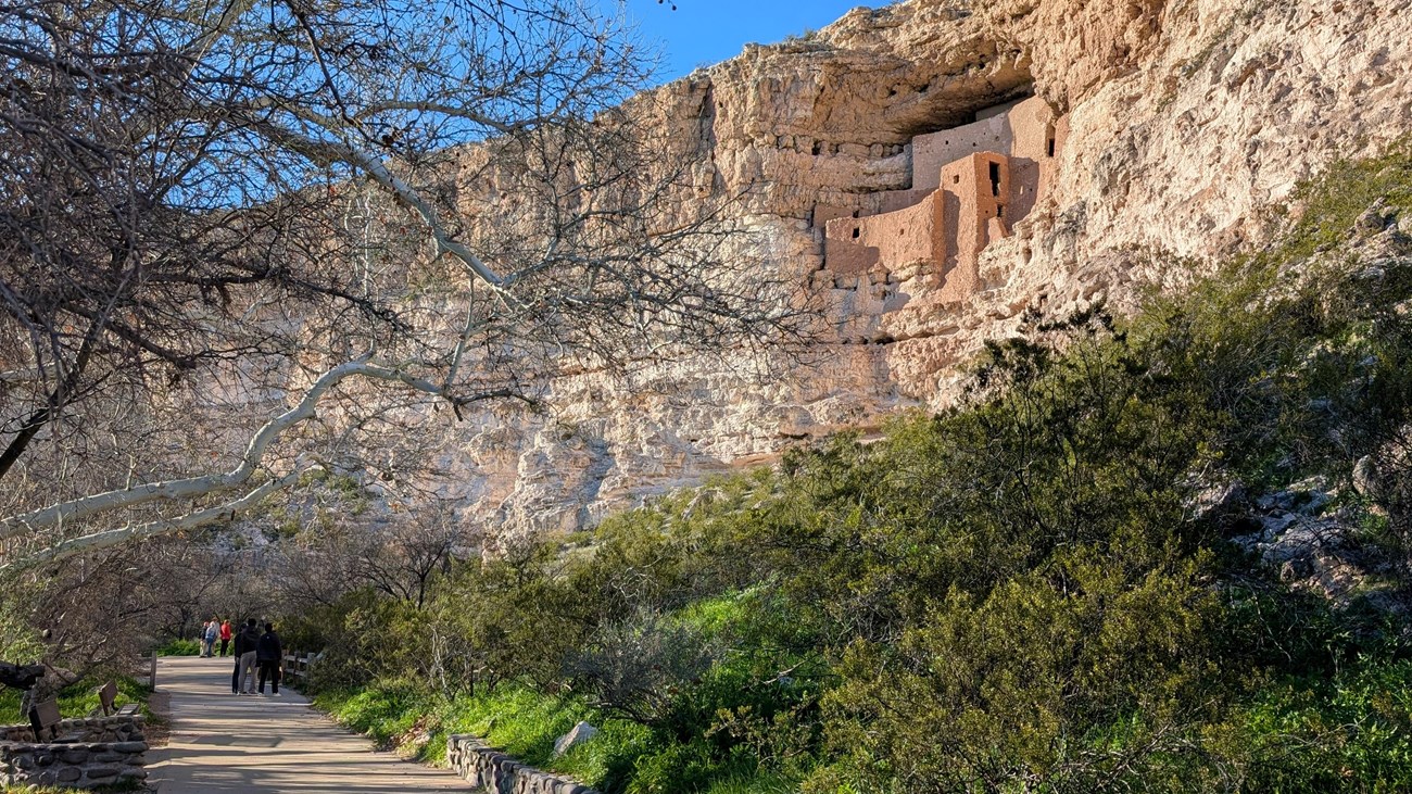 a large, multi-story adobe dwelling inside a large alcove on the side of a cliff