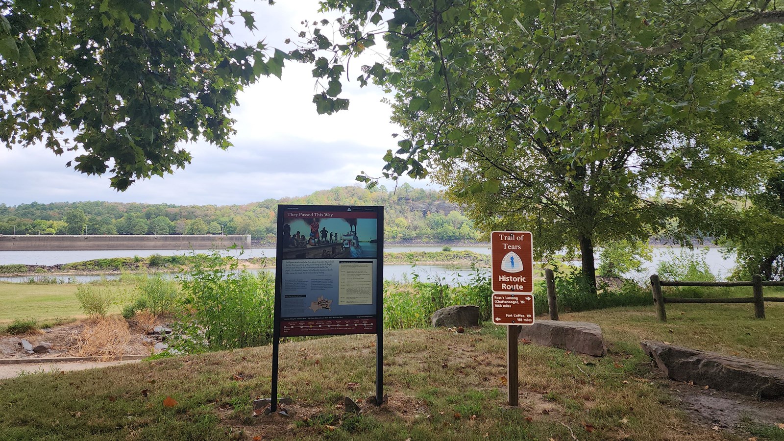 Trail of Tears exhibit and mileage sign with river and lock and dam behind.