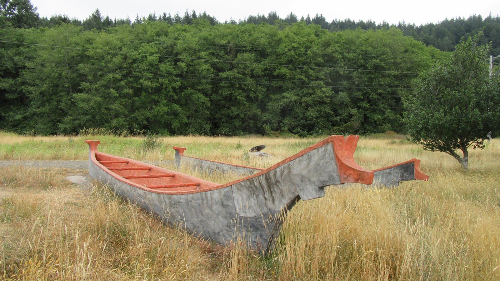 Wooden canoe in grassy field. 