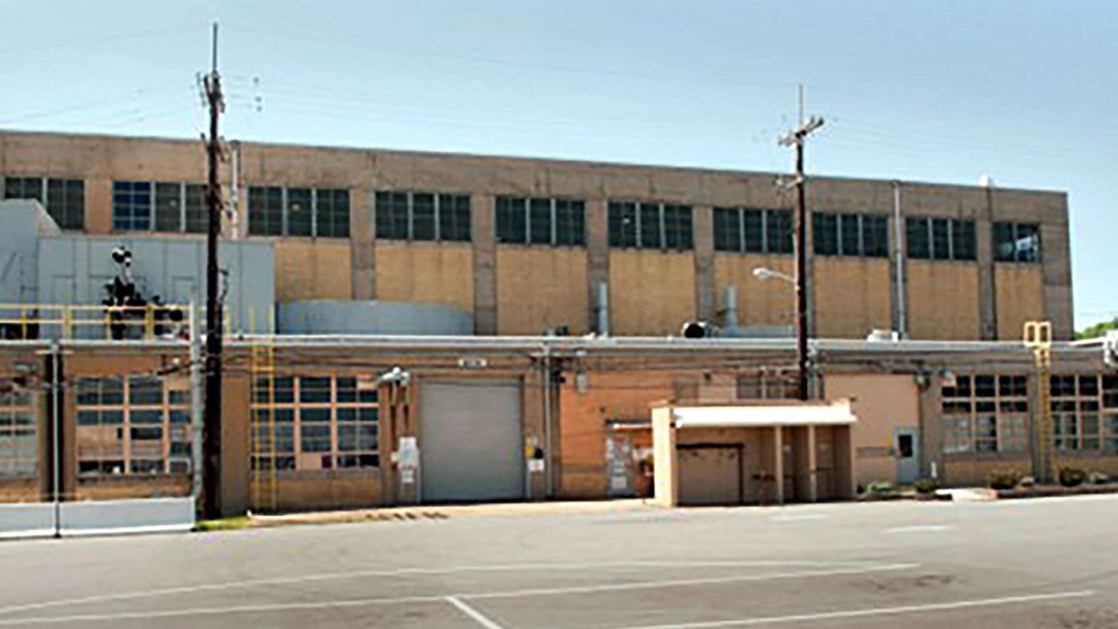 A tan two-story industrial building with powerlines and loading dock