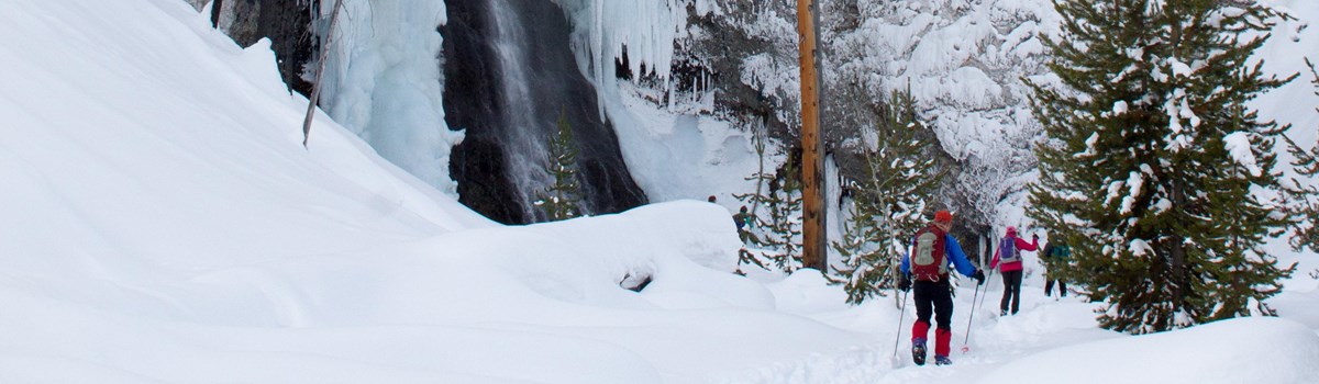 Skiers make their way to the bottom of frozen Fairy Falls in winter.