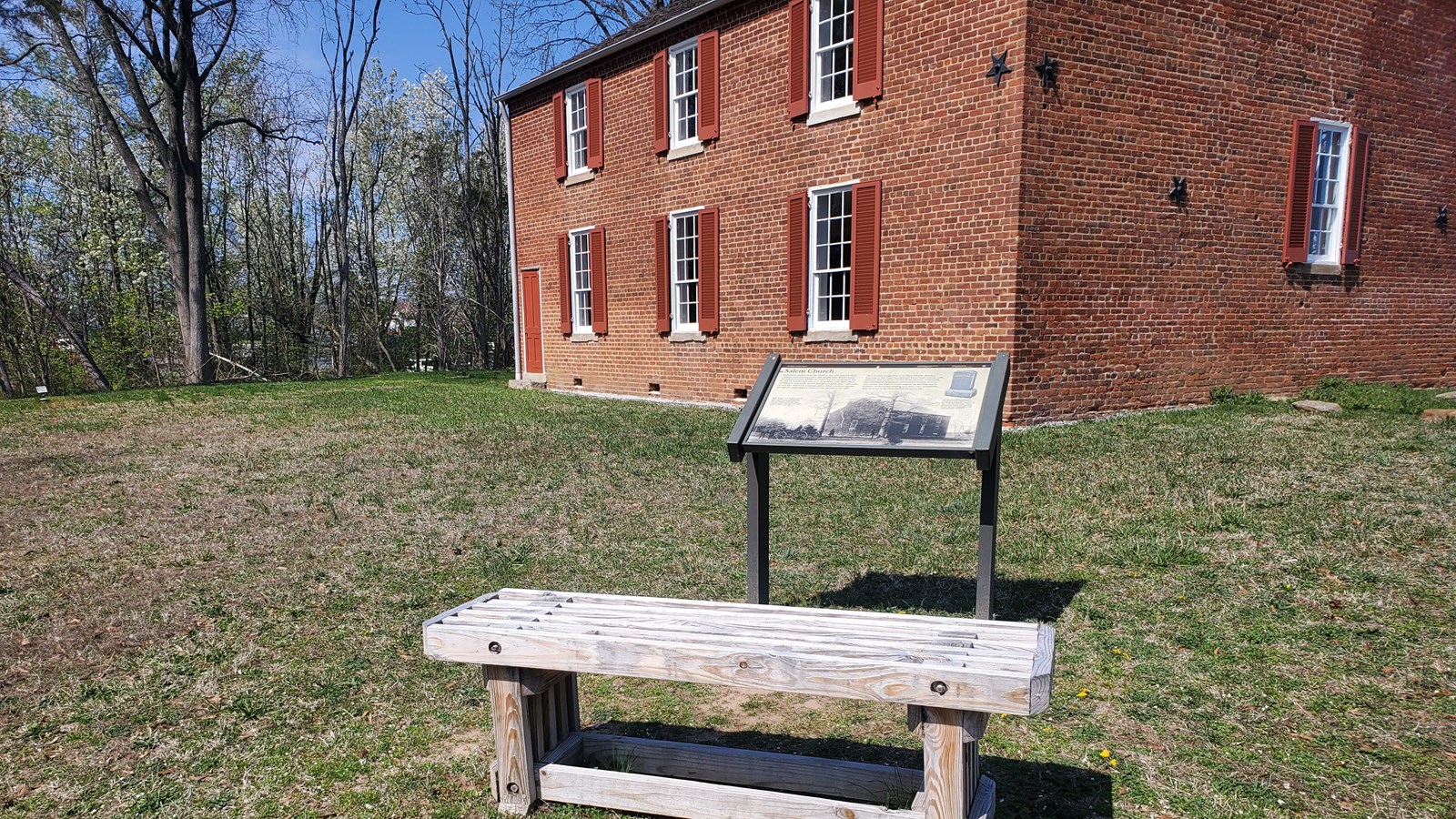 A sign sits in front of a historic church with a side door.