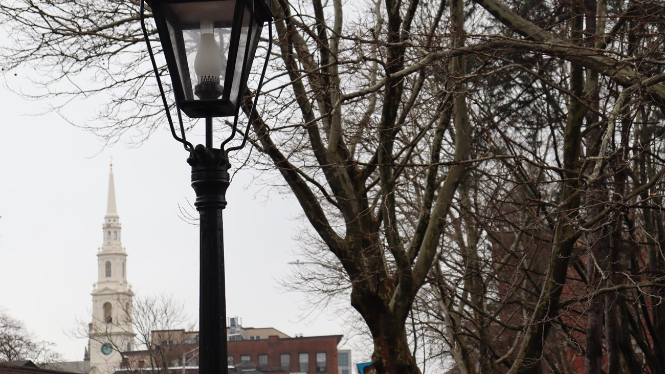 An historic lamp post, steeple, and trees