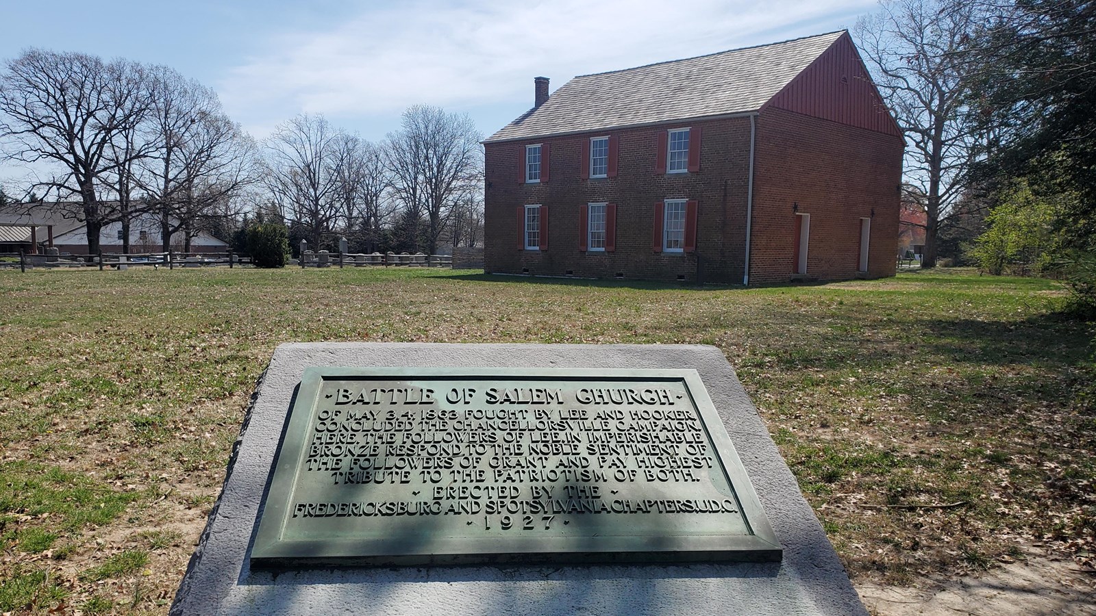 A metal plaque on stone base in front of a historic church.