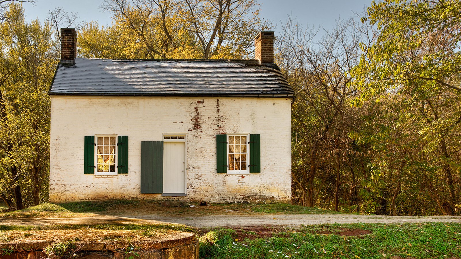 A white lockhouse sits across the towpath. 