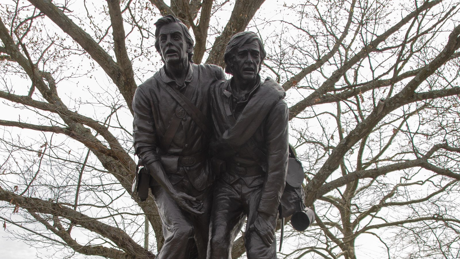 A large bronze statue depicting two individuals from opposing armies holding each other. 
