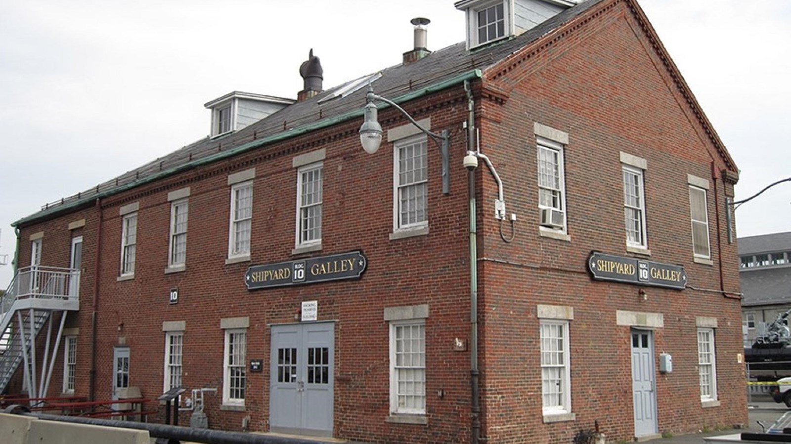 Red rectangular brick building, 2 stories, 7 windows across on long side, 3 windows on short side.