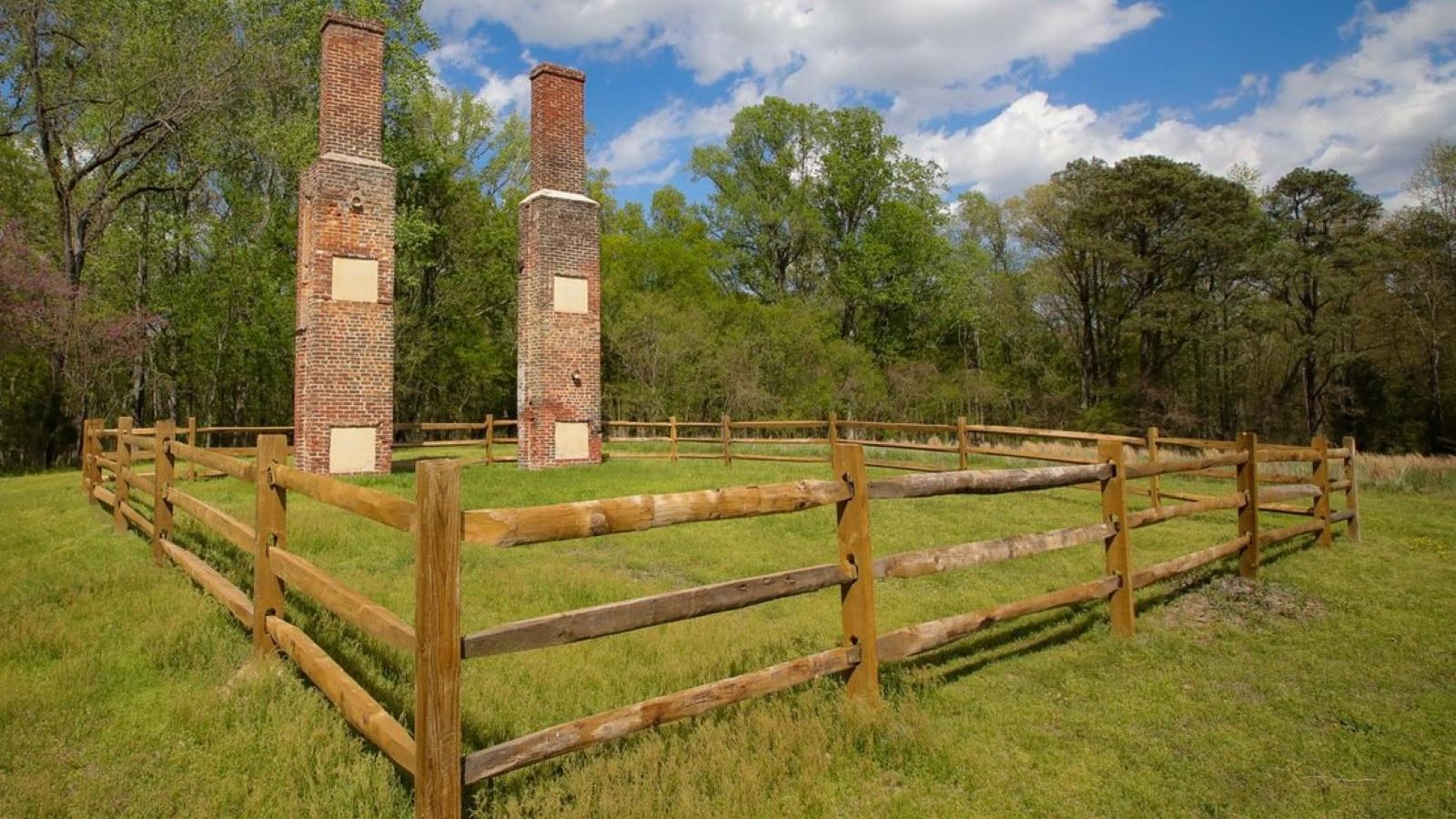 Two brick chimneys stand in a fenced field, the remains of the Willis Church parsonage.