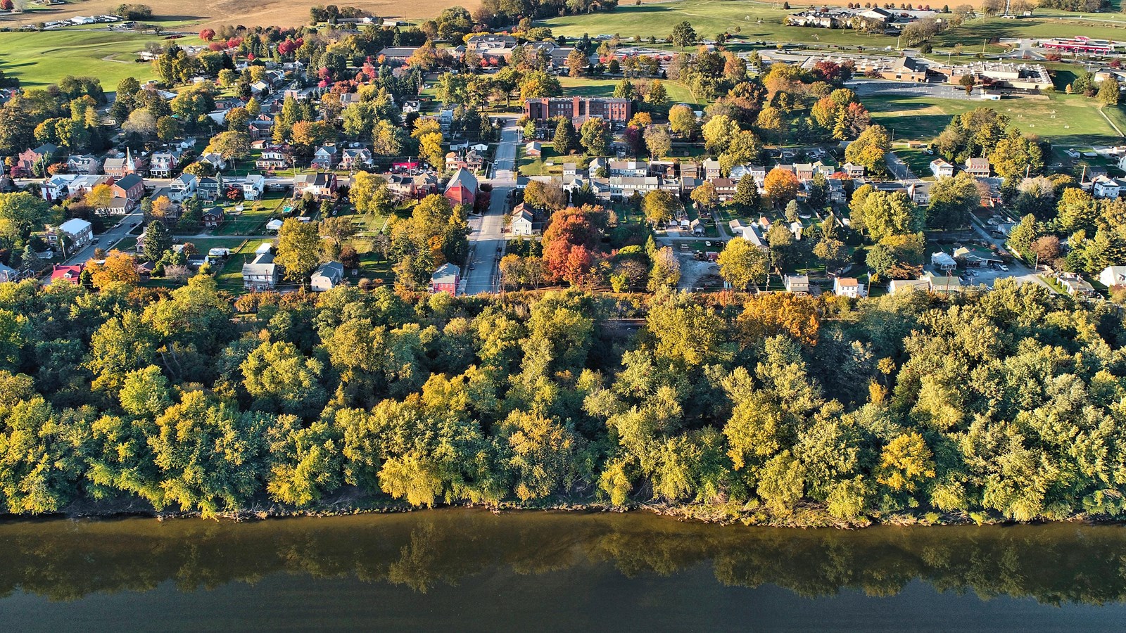 Aerial view of Marietta, PA with a river in the foreground, dense tree line, and a grid-like layout.