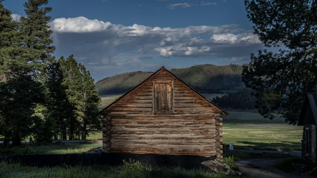 A historic log building overlooking a montane grassland.