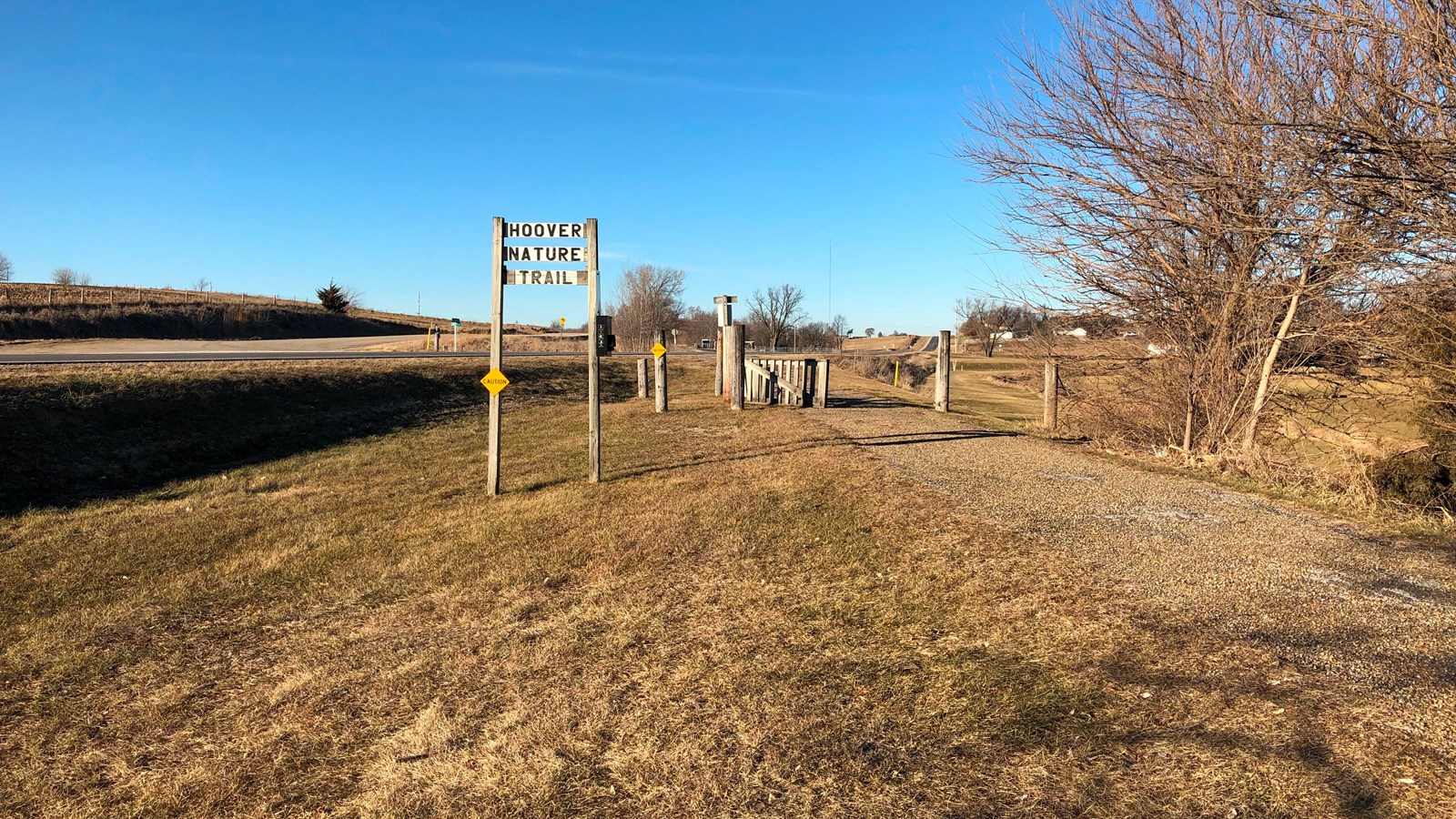 A wooden sign marks a rural nature trail along an old railway grade. 