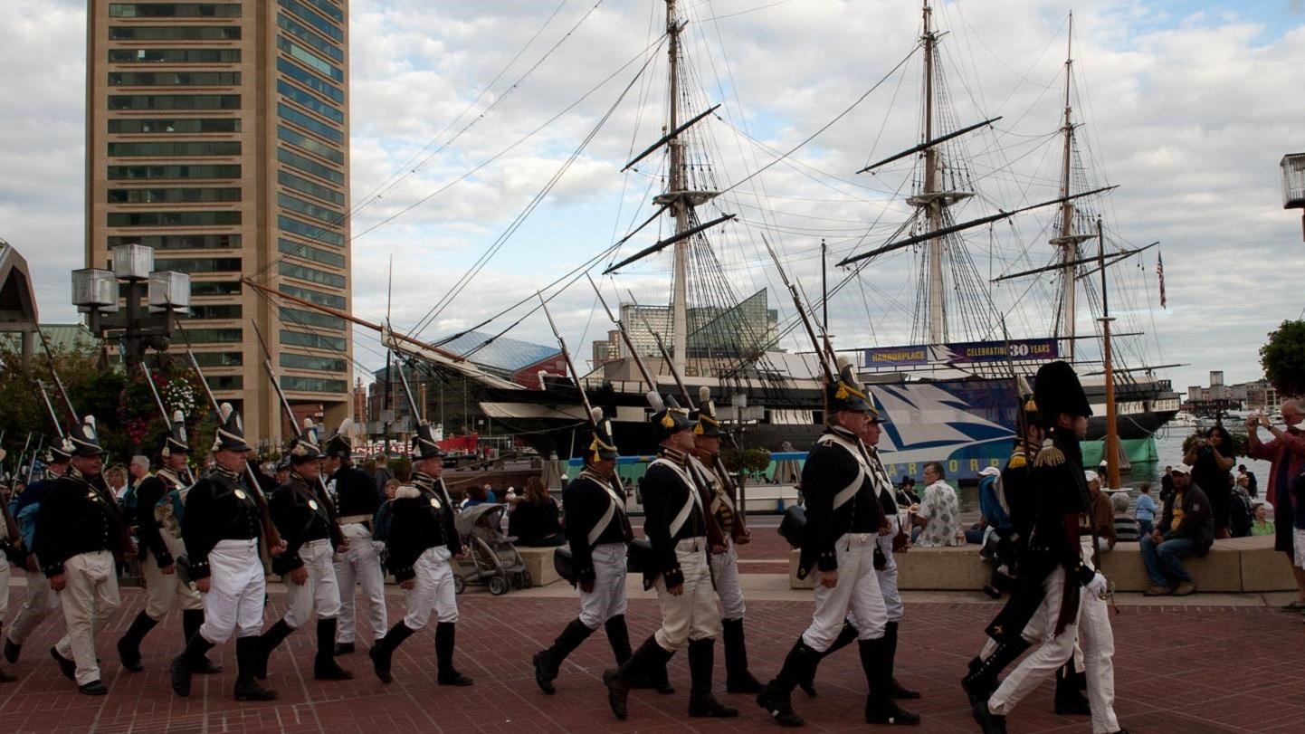 A line of soldiers in kit marching in present day Baltimore.