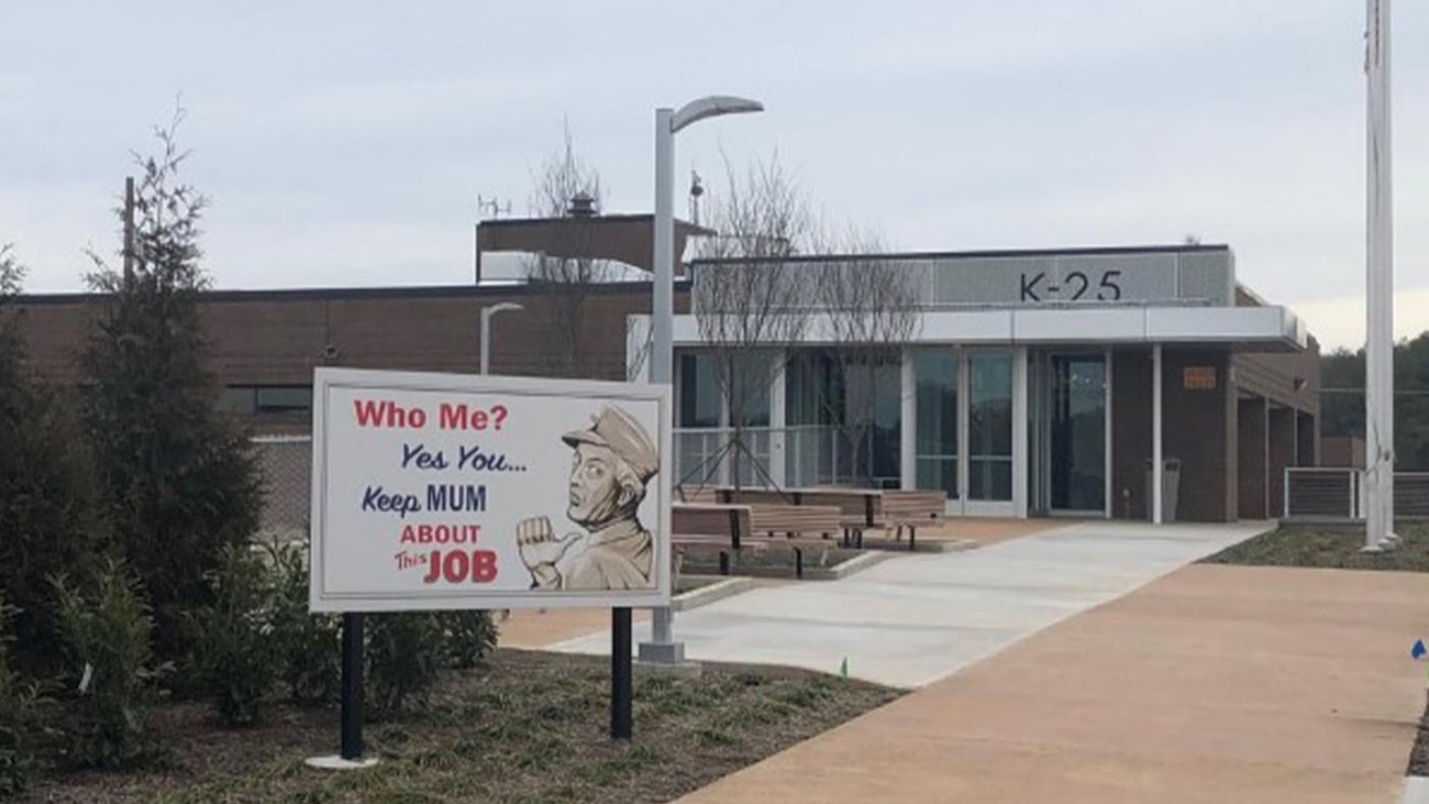 A small museum building with several retro billboards on the walkway in front of it.