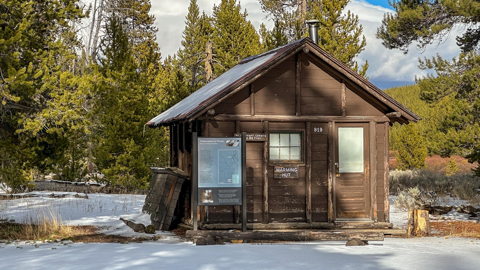 Wooden hut with NPS arrowhead mounted under eaves surrounded by snow