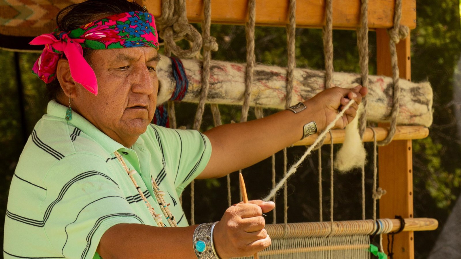 Fiber artist Roy Kady demonstrating weaving to a group.