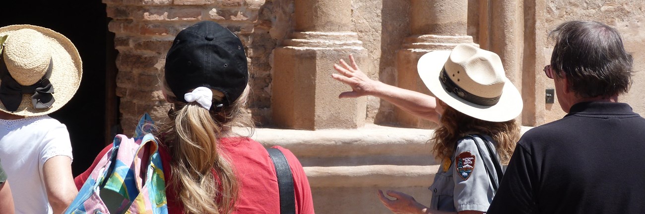 ranger pointing to front of church, visitors listening