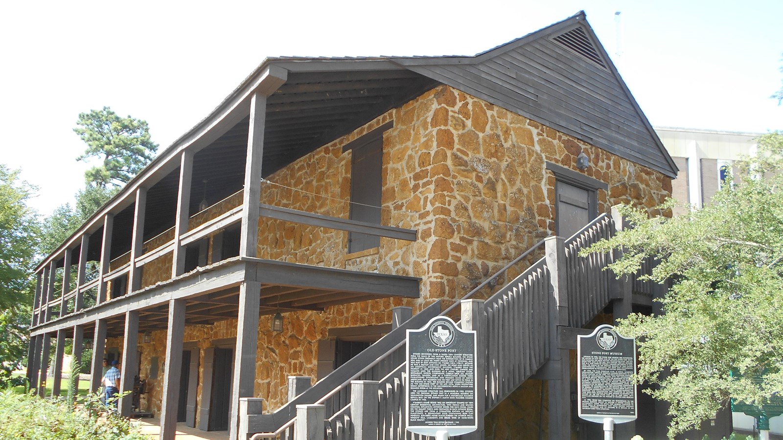 A large two story, stone building with a large porch.