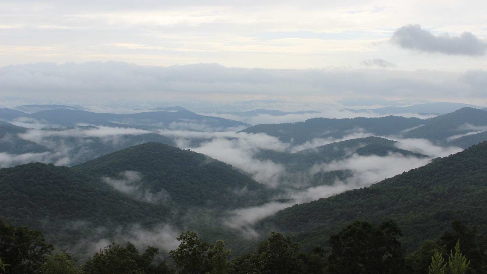 Layered green mountains with clouds in the valleys