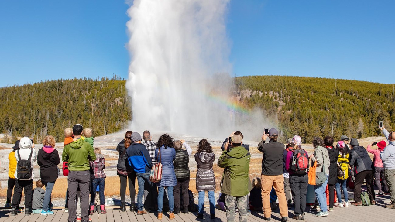 Visitors watch an eruption of Old Faithful Geyser.