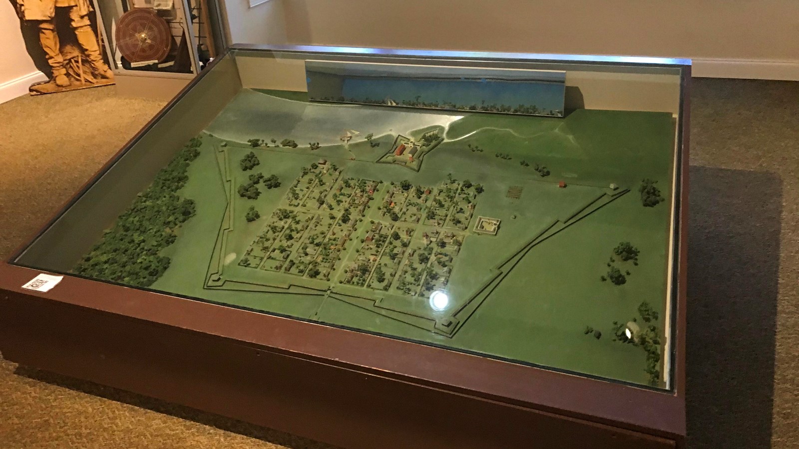 Shadowbox with town model showing star-shaped fort, settlers plots, town wall, and trees surrounding