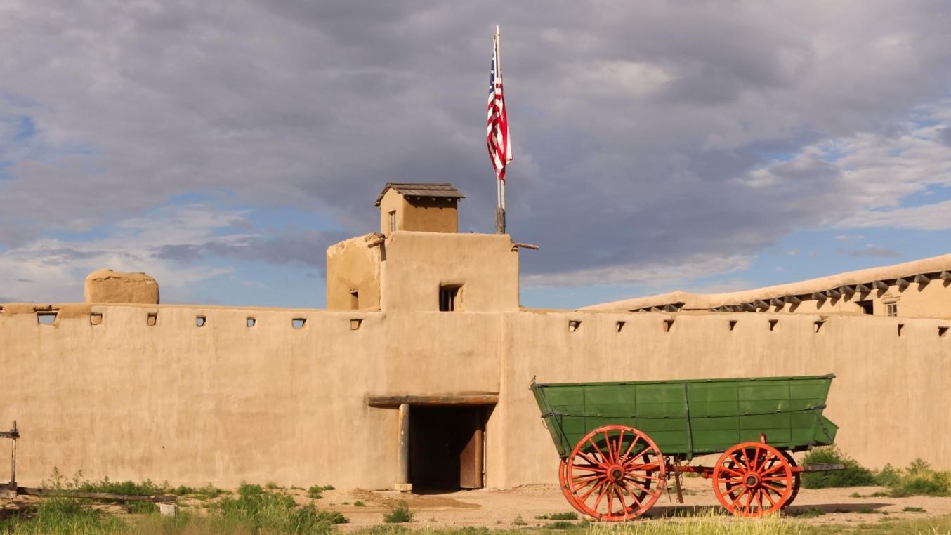 A tall adobe fortress with a round tower on one side .
