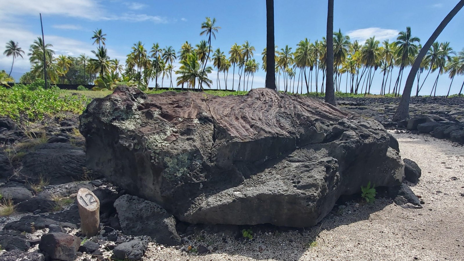 A large rectangular lava rock boulder propped at an angle creating a small space under one side.