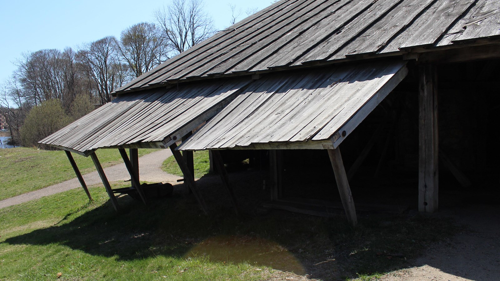 Open-air wood shed with sand floor connected to large stone furnace.