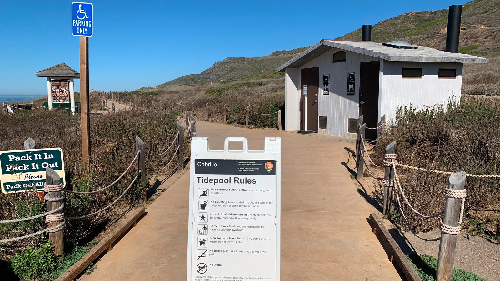 White A-frame sign stands in middle of tan concrete walkway