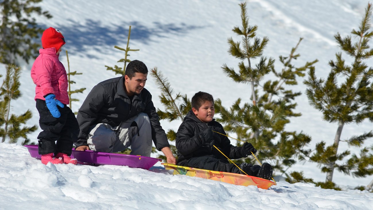 a family preparing to sled down a snowy hill