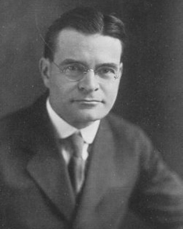 Man in suit and glasses poses for picture