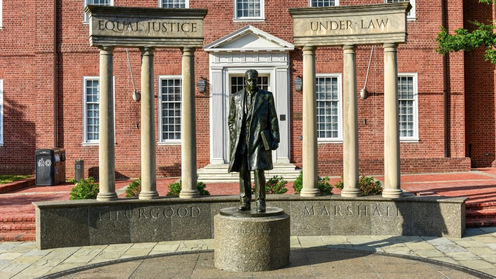 A bronze statue of a man stands on a pedestal between pillars.
