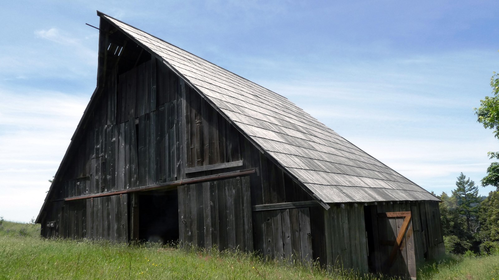 Green grass surrounds a two-story wooden barn.