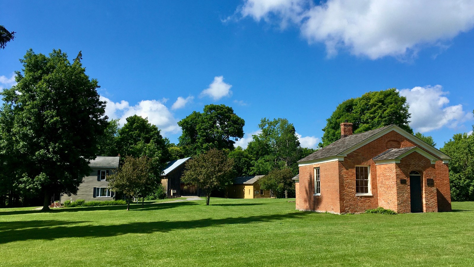 Four historic buildings with trees in the background.