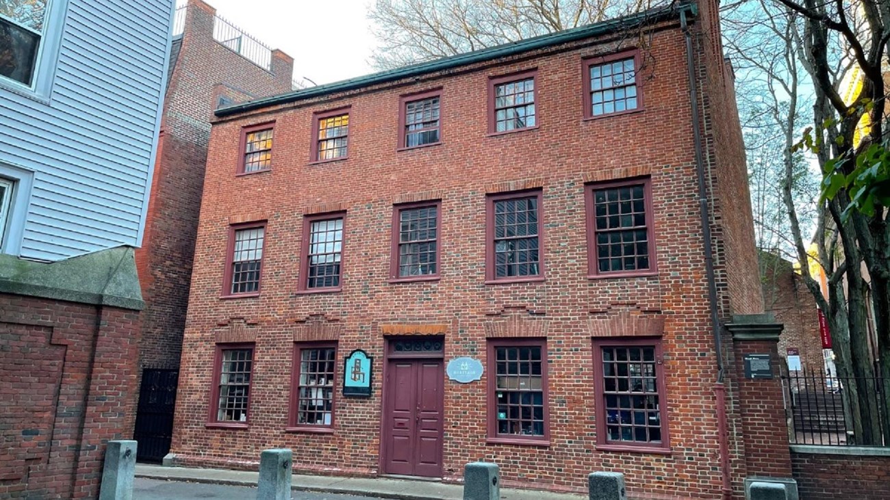 A three-story brick building with three rows of five paned glass windows.