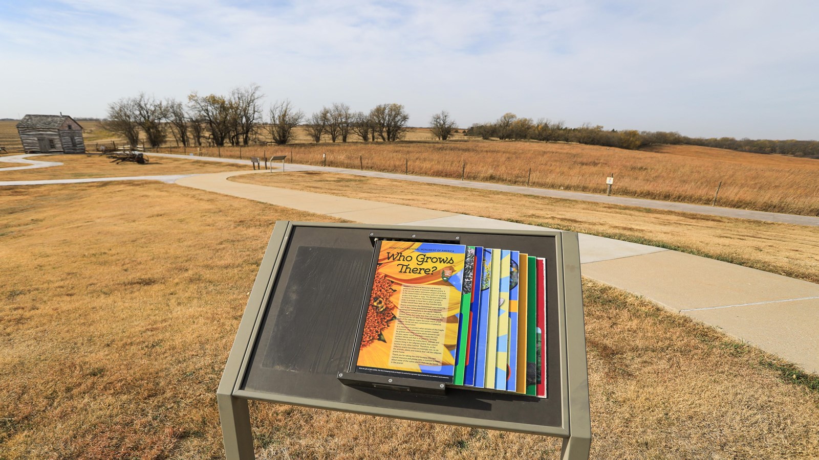 A wayside stands in front of open prairie with some trees in the background.