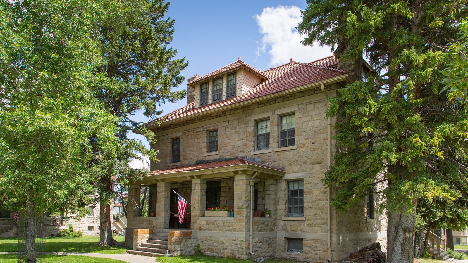 A historic building made of stone with a roof with red shingles.