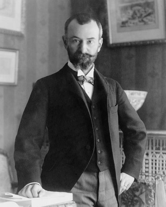 A black and white photo of a man with a beard and close cropped hair stares into the camera