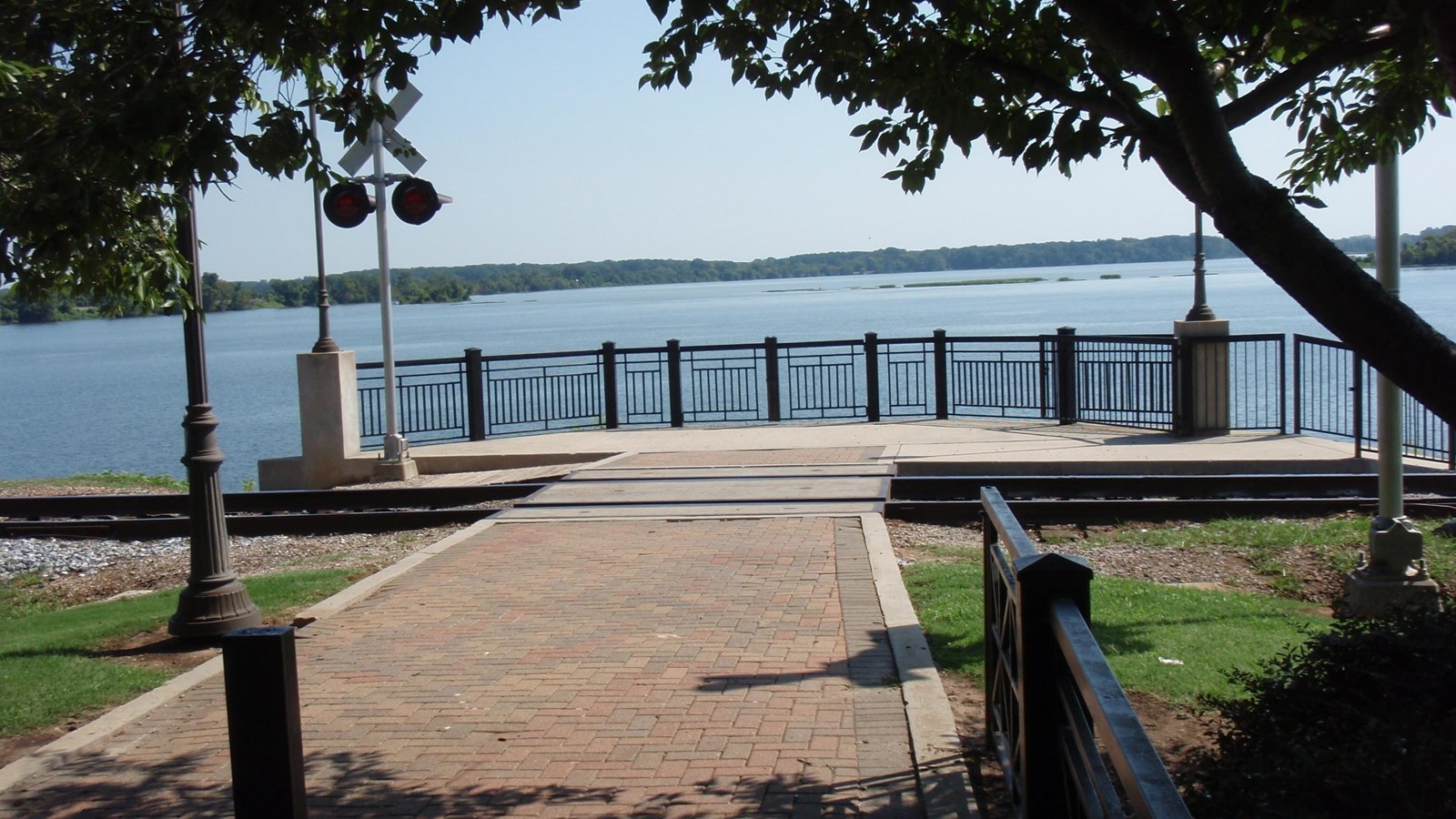 A red brick path leads out to a viewpoint over an expansive lake.