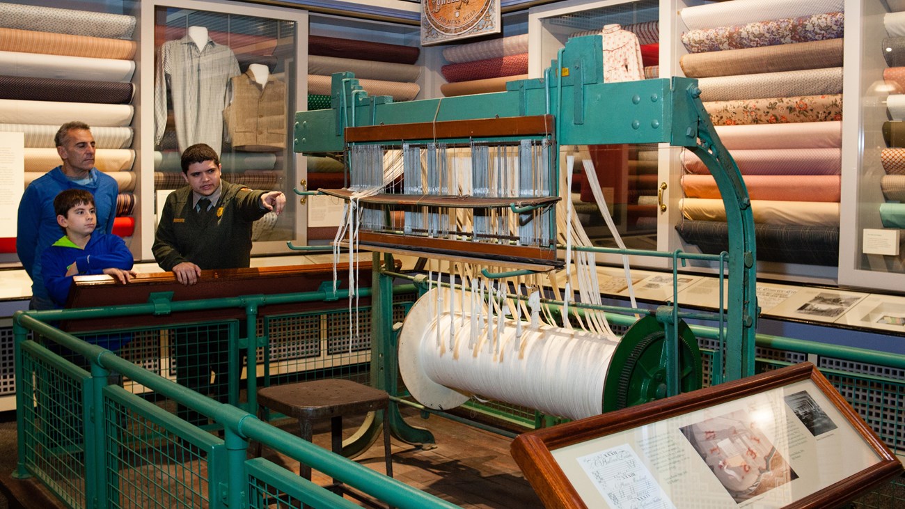 A park ranger shows off historic artifacts to a father and son in a museum