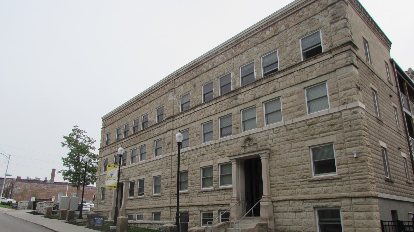 Stone facade apartment building, four stories, windows at each level, two entrances on main side